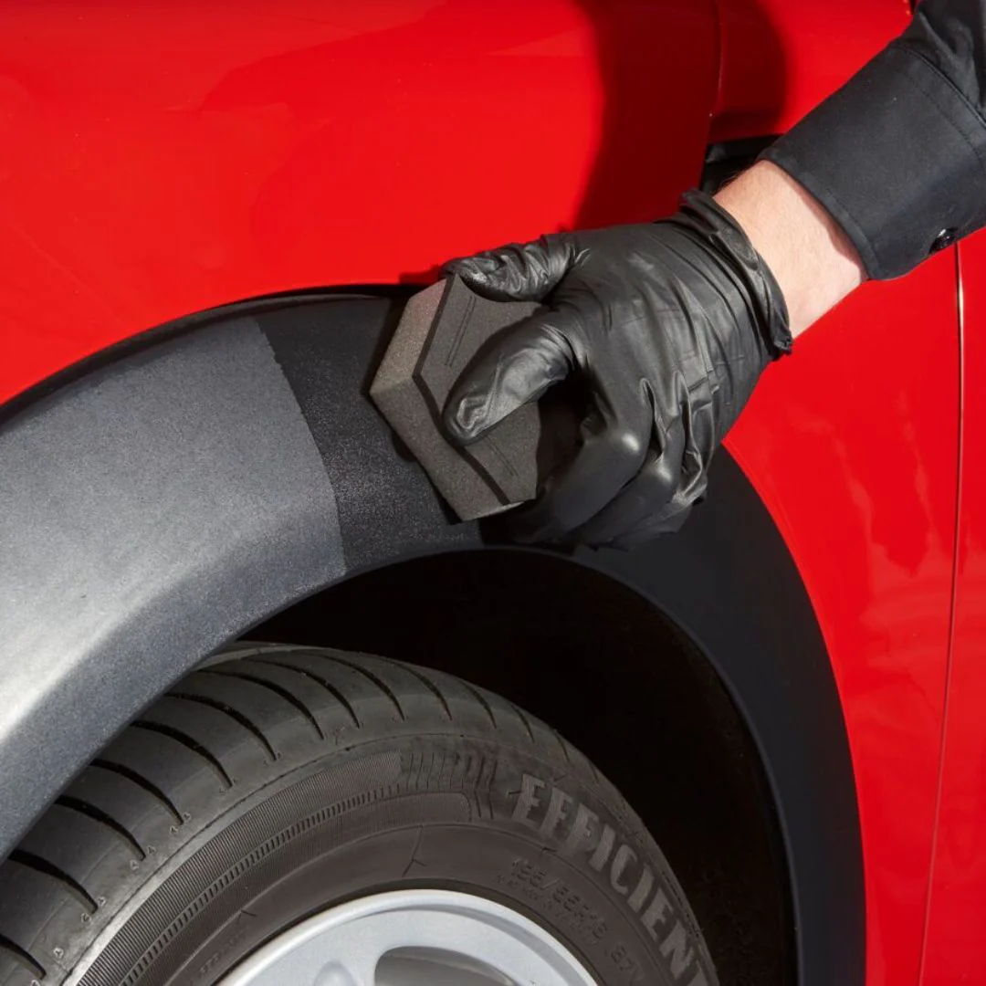 A black trim bumper of a red car being restored and detailed