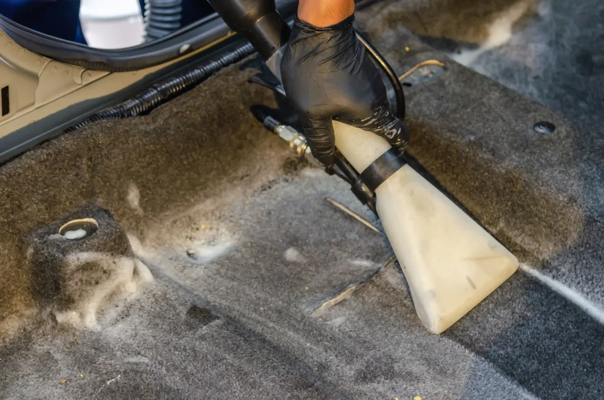 Vacuuming a car interior seam by seam during a professional detail